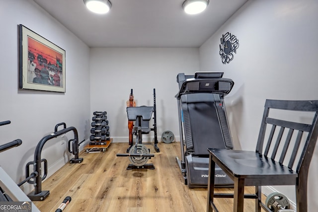 exercise room with baseboards and wood finished floors