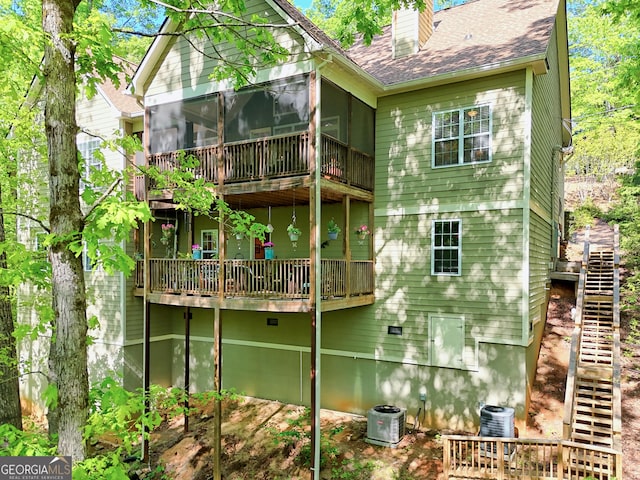 back of house featuring a chimney, a sunroom, central AC unit, stairs, and a shingled roof