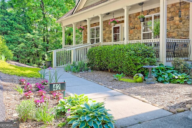 view of exterior entry featuring covered porch and stone siding