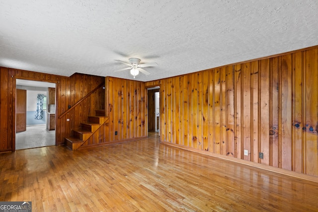 7255 Blue Ridge Dr, Blue Ridge, GA 30513 - unfurnished living room featuring wooden walls, ceiling fan, a textured ceiling, hardwood / wood-style flooring, and stairway