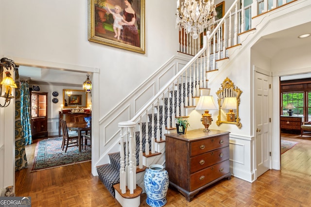 4584 E Conway Dr, Atlanta, GA 30327 - staircase with an inviting chandelier, a towering ceiling, a decorative wall, and a wainscoted wall