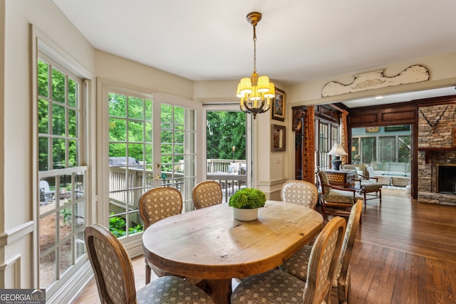 4584 E Conway Dr, Atlanta, GA 30327 - dining room with an inviting chandelier, dark wood-style flooring, a healthy amount of sunlight, and a stone fireplace