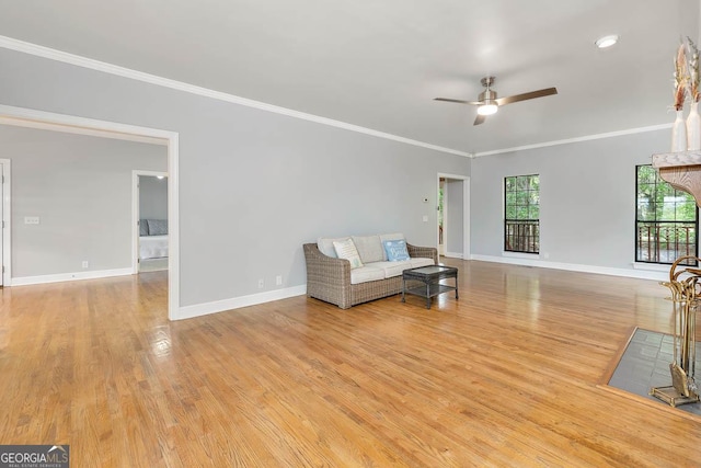 living area with baseboards, ornamental molding, a ceiling fan, and wood finished floors