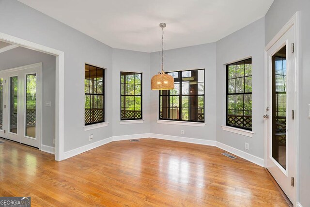 unfurnished dining area with visible vents, a healthy amount of sunlight, and light wood-style flooring