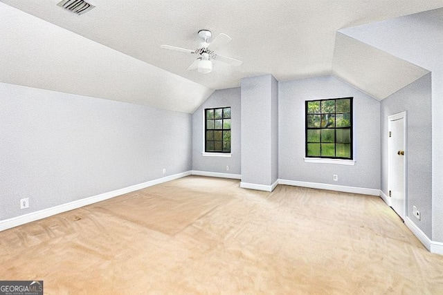 additional living space with baseboards, visible vents, lofted ceiling, and carpet