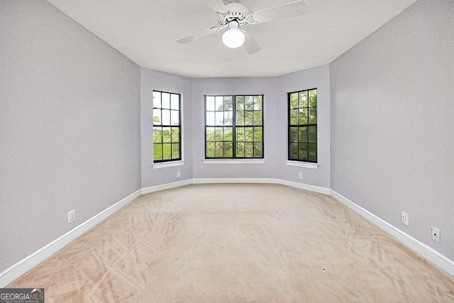 carpeted empty room featuring baseboards and a ceiling fan