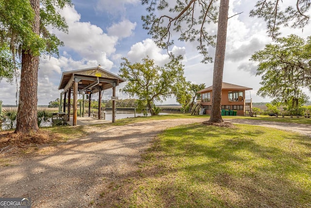 view of home's community featuring a yard, a water view, driveway, and stairs