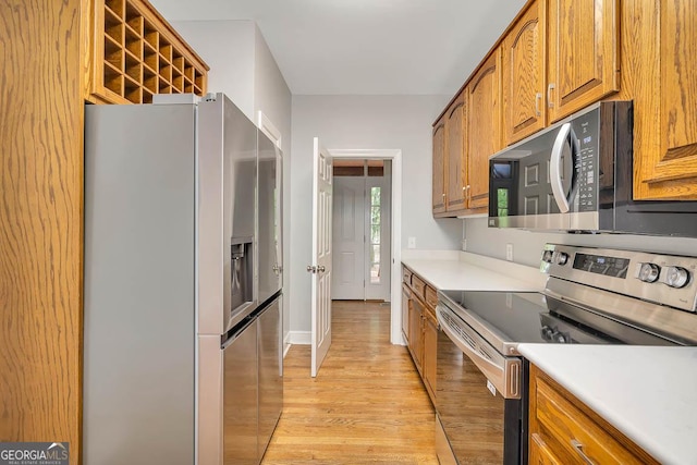 kitchen with brown cabinets, light countertops, appliances with stainless steel finishes, and light wood-type flooring