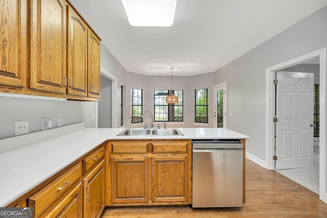 kitchen featuring stainless steel dishwasher, a peninsula, brown cabinets, a sink, and light wood-style flooring