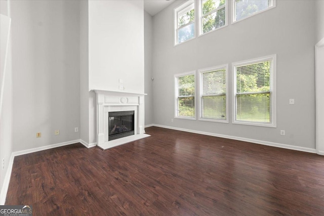 145 Redsage Rdg, Atlanta, GA 30349 - unfurnished living room with a fireplace, dark wood finished floors, baseboards, and a high ceiling