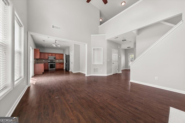 145 Redsage Rdg, Atlanta, GA 30349 - unfurnished living room featuring a towering ceiling, a ceiling fan, dark wood finished floors, baseboards, and a chandelier