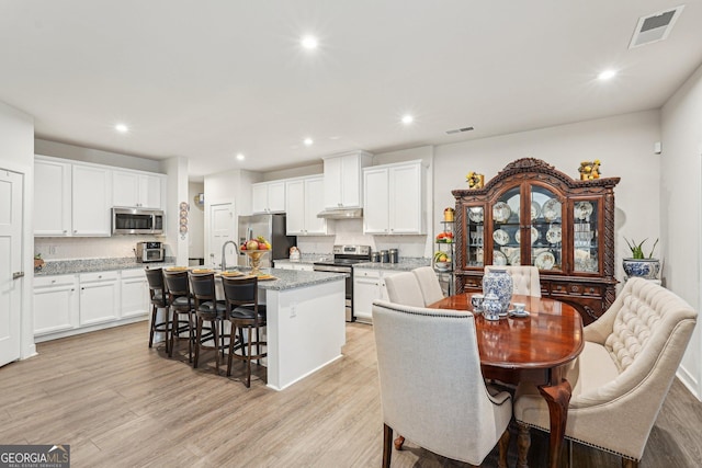 dining space with recessed lighting and light wood-style floors