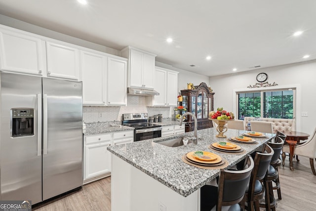 kitchen featuring appliances with stainless steel finishes, a sink, under cabinet range hood, recessed lighting, and white cabinets