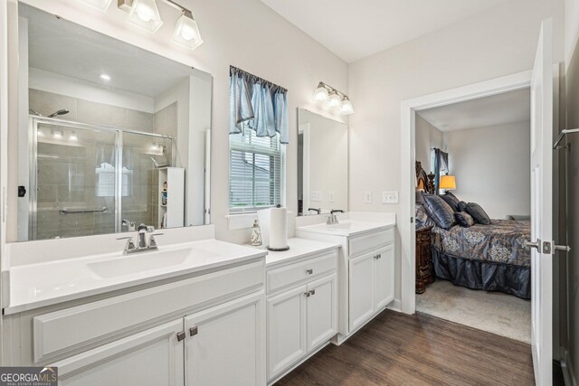 ensuite bathroom featuring a stall shower, vanity, and wood finished floors