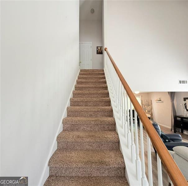 staircase featuring baseboards and visible vents