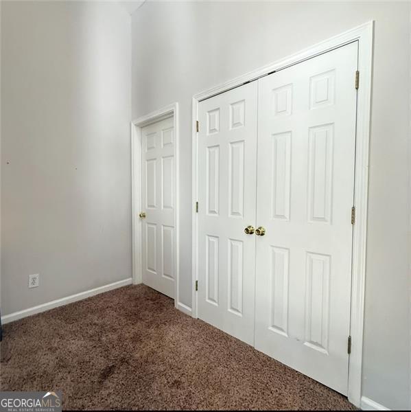 unfurnished bedroom with carpet floors, baseboards, and a closet