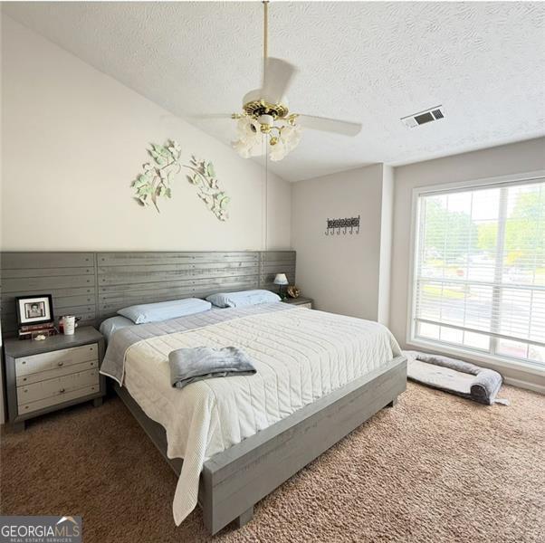 bedroom featuring visible vents, a textured ceiling, and carpet