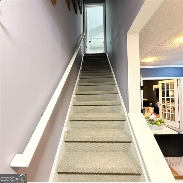 staircase with a paneled ceiling