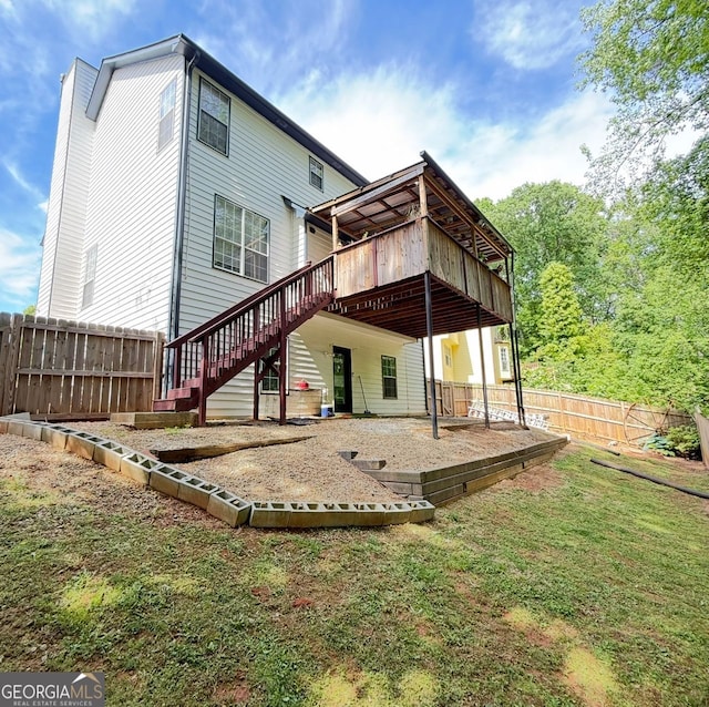 back of house featuring a wooden deck, fence, a patio, stairs, and a lawn
