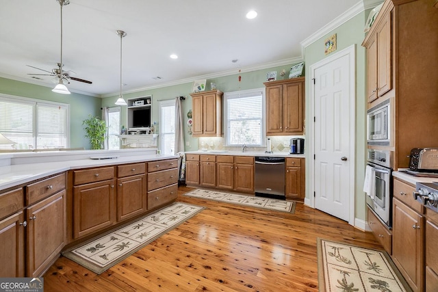 kitchen with brown cabinets, light countertops, light wood-style flooring, stainless steel appliances, and a ceiling fan