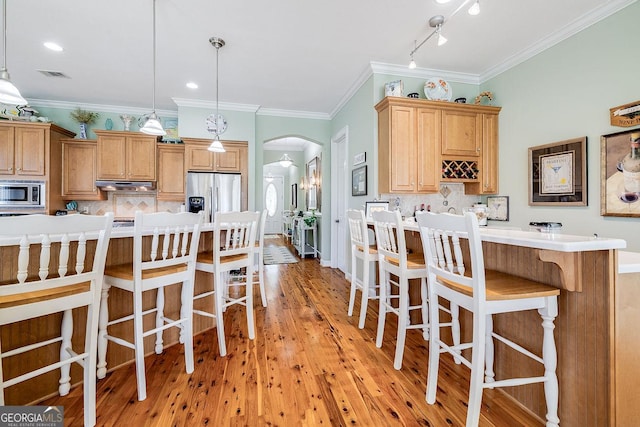 kitchen featuring a kitchen bar, visible vents, appliances with stainless steel finishes, arched walkways, and under cabinet range hood