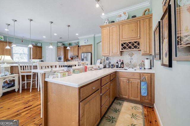 kitchen with decorative backsplash, appliances with stainless steel finishes, hanging light fixtures, light wood-type flooring, and a peninsula