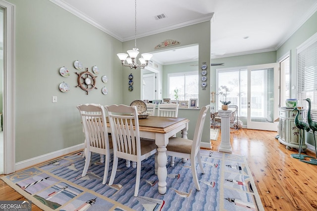dining space with crown molding, wood finished floors, a notable chandelier, and visible vents