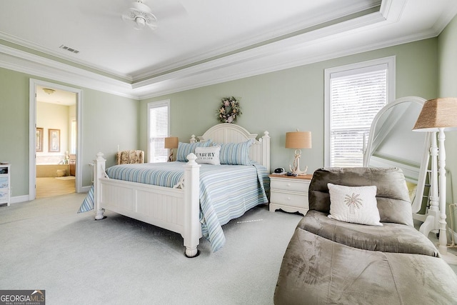 carpeted bedroom with crown molding, a tray ceiling, visible vents, and connected bathroom