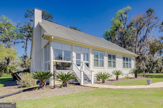 view of front of property with a chimney, crawl space, a sunroom, and a front yard