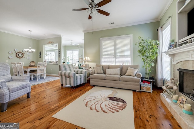 living area with a fireplace with raised hearth, ceiling fan with notable chandelier, and hardwood / wood-style floors