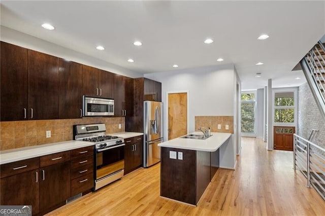 1294 Fernwood Cir NE, Brookhaven, GA 30319 - kitchen featuring a peninsula, light countertops, light wood-style flooring, backsplash, and stainless steel appliances