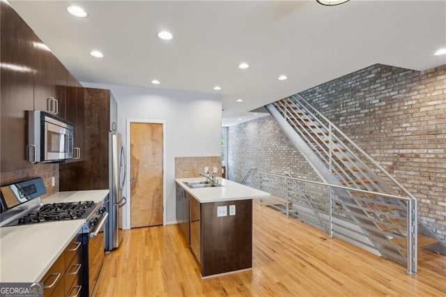 1294 Fernwood Cir NE, Brookhaven, GA 30319 - kitchen featuring light wood-style floors, appliances with stainless steel finishes, brick wall, and light countertops