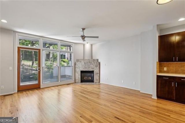 1294 Fernwood Cir NE, Brookhaven, GA 30319 - unfurnished living room with a ceiling fan, a glass covered fireplace, recessed lighting, and light wood-type flooring