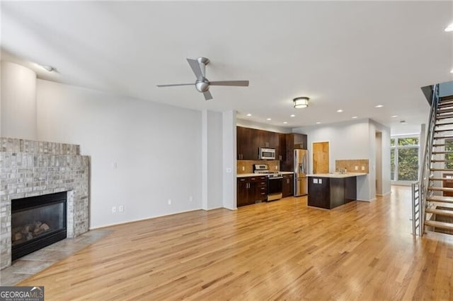 1294 Fernwood Cir NE, Brookhaven, GA 30319 - living area with a brick fireplace, stairway, recessed lighting, a ceiling fan, and light wood finished floors
