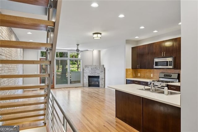 1294 Fernwood Cir NE, Brookhaven, GA 30319 - kitchen featuring decorative backsplash, ceiling fan, dark brown cabinets, a glass covered fireplace, and stainless steel appliances