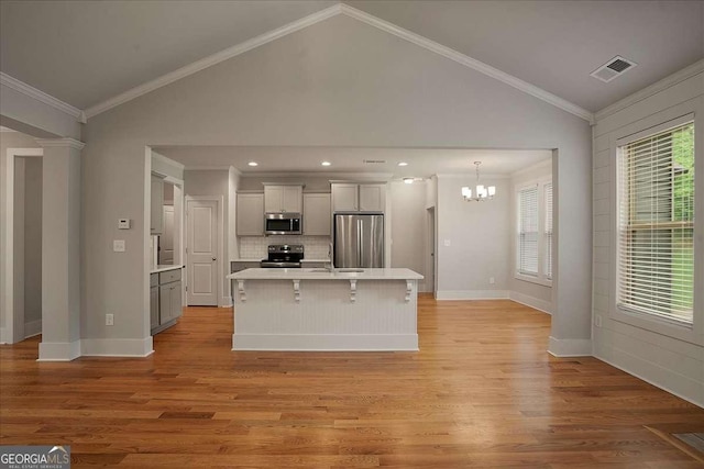 kitchen with appliances with stainless steel finishes, visible vents, light countertops, a chandelier, and vaulted ceiling