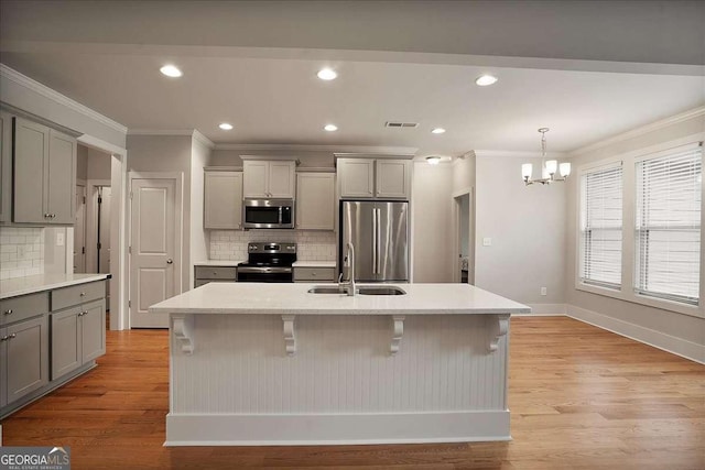 kitchen featuring gray cabinetry, appliances with stainless steel finishes, ornamental molding, and an inviting chandelier