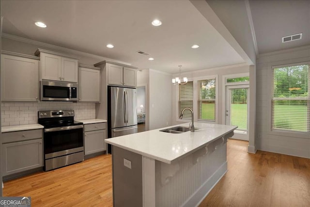 kitchen featuring crown molding, a sink, gray cabinetry, and stainless steel appliances