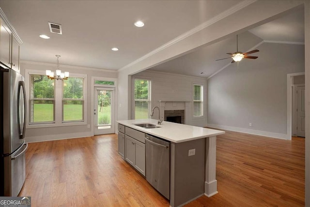 kitchen featuring visible vents, a fireplace, open floor plan, a sink, and appliances with stainless steel finishes