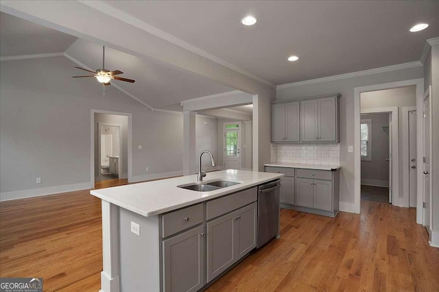 kitchen with a sink, light countertops, baseboards, stainless steel dishwasher, and gray cabinetry