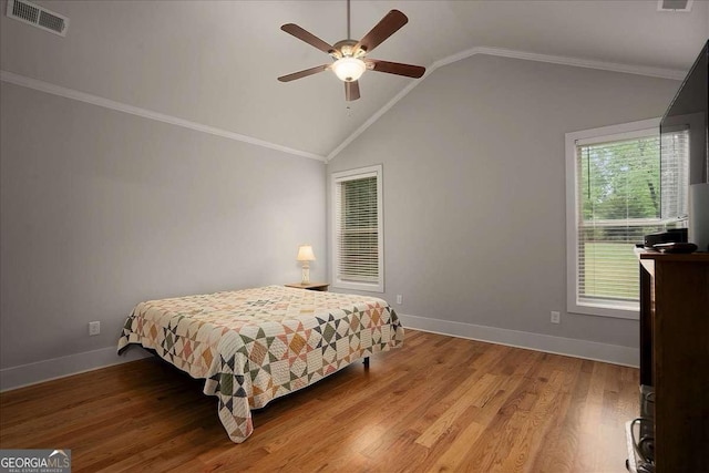 bedroom featuring visible vents, crown molding, lofted ceiling, wood finished floors, and baseboards