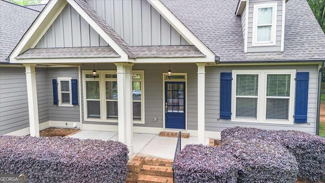 view of exterior entry with a porch, board and batten siding, and roof with shingles