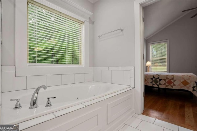 bathroom with vaulted ceiling, plenty of natural light, tile patterned flooring, and a jetted tub
