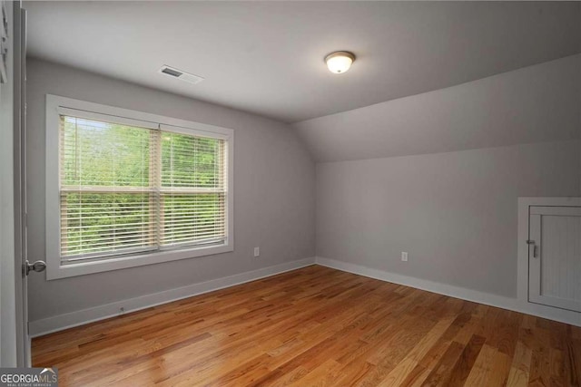bonus room featuring visible vents, light wood-style floors, baseboards, and vaulted ceiling