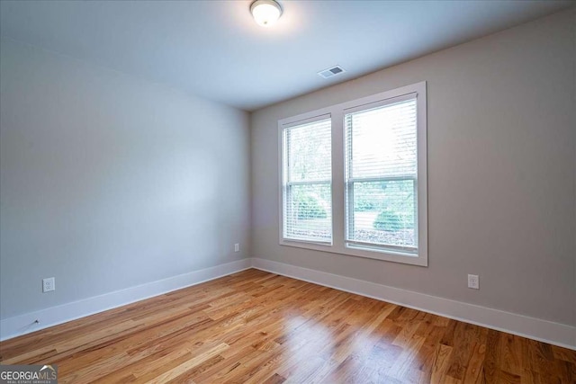 unfurnished room with baseboards, light wood-type flooring, and visible vents