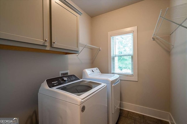 washroom featuring independent washer and dryer, dark tile patterned flooring, baseboards, and cabinet space