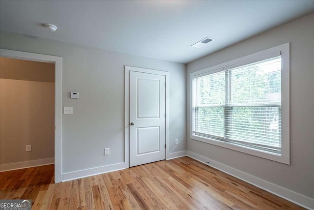 unfurnished bedroom with visible vents, light wood-style floors, baseboards, and a closet