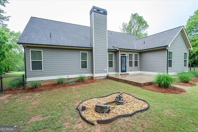 back of house featuring a chimney, roof with shingles, a patio area, fence, and a yard