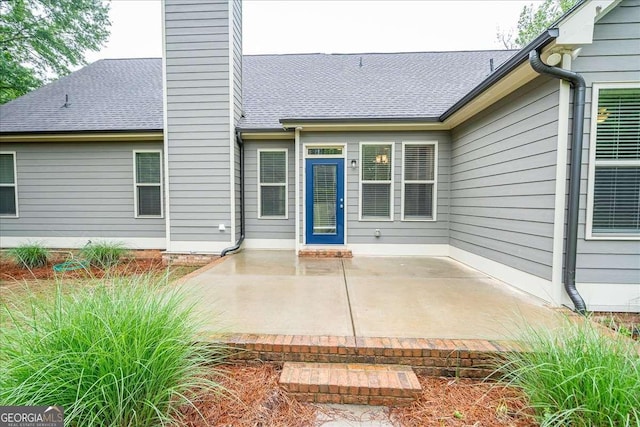 view of exterior entry with a patio area and a chimney