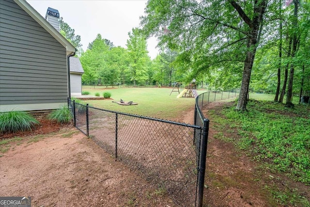 exterior space featuring a playground, fence, and a lawn